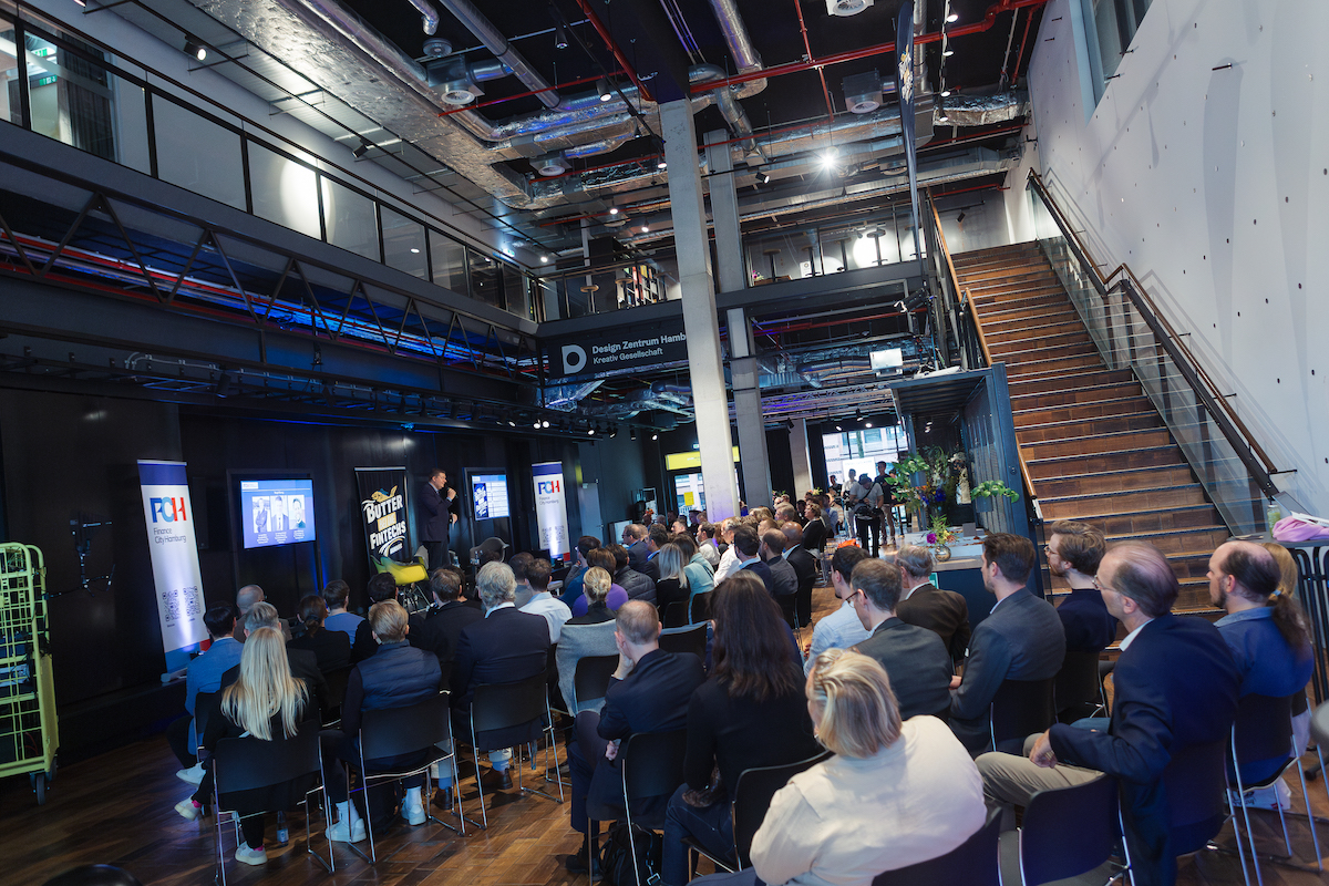 Menschen blicken auf eine Bühne während des Hamburger Fintech Day 2024, Finanzsenator Dr. Andreas Dressel spricht