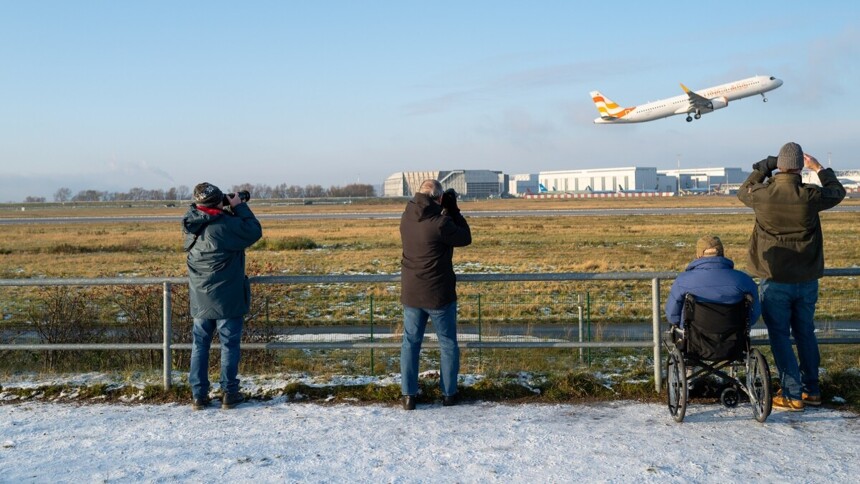 Visitors watch an airplane taking off from the Finkenwerder industrial area