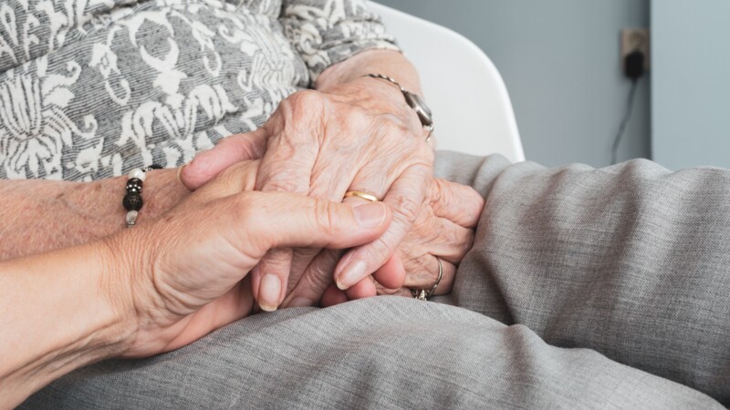 Hand ergreift Hände einer alten Frau