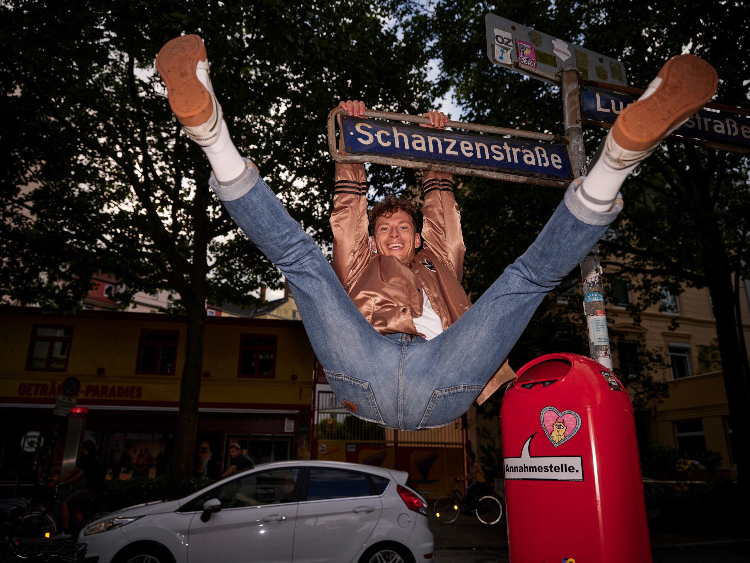 A man swings from the Sternschanze street sign 