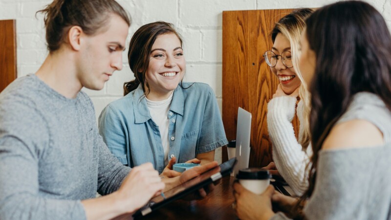 Drei Frauen und ein Mann, die an einem Tisch sitzen und gemeinsam brainstormen