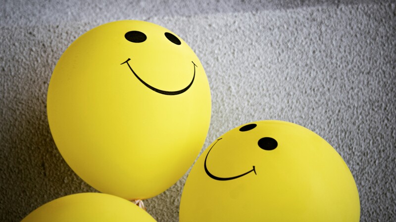 Drei gelbe Luftballons mit Smiley-Gesicht