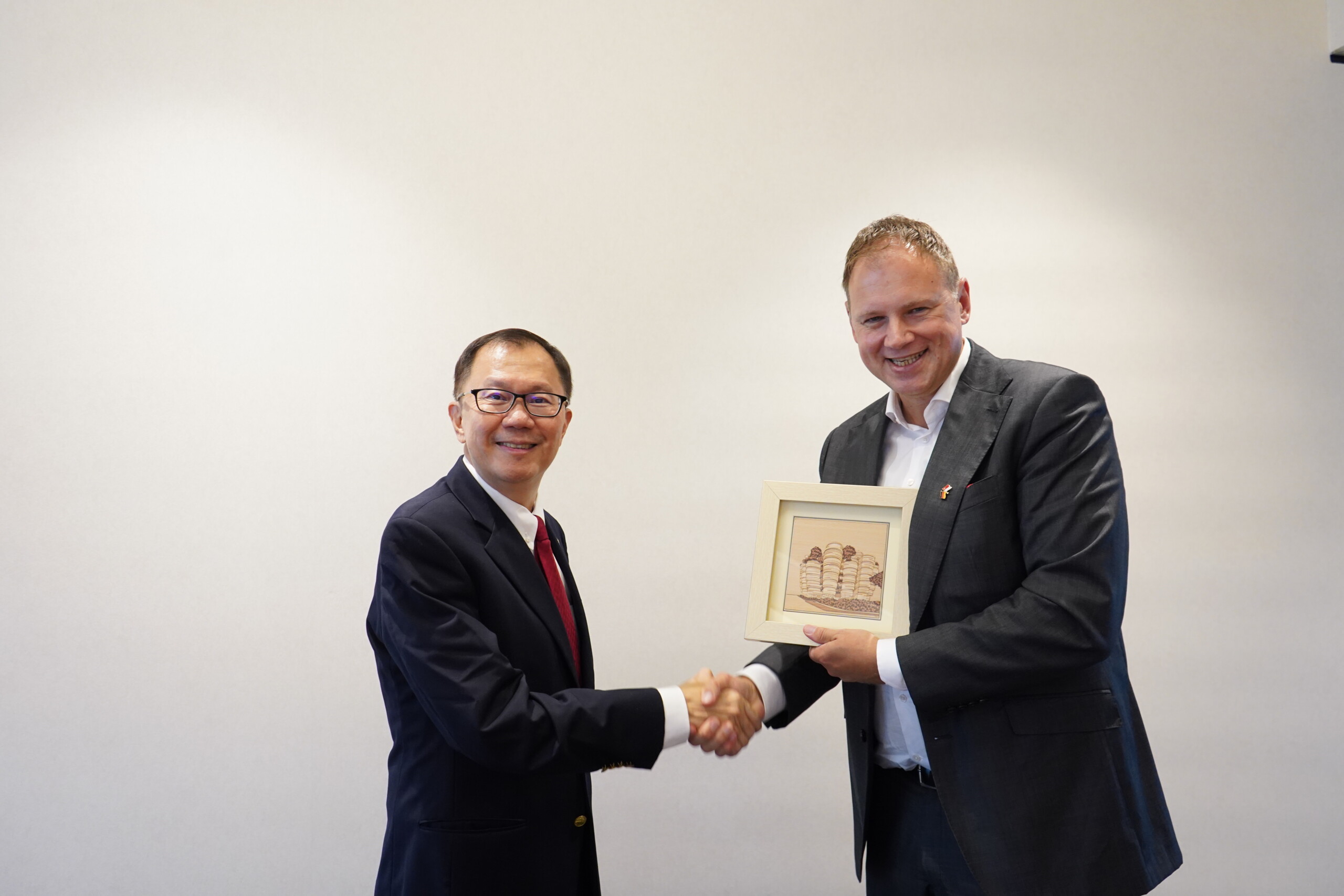 Professor Ho Teck Hua (l.) überreicht Prof. Dr. Hauke Heekeren einen Kunstdruck mit einer architektonischen Anmutung des NTU-Campus