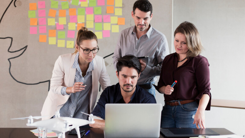 Vier junge Leute beim Brainstorming vor Rechner